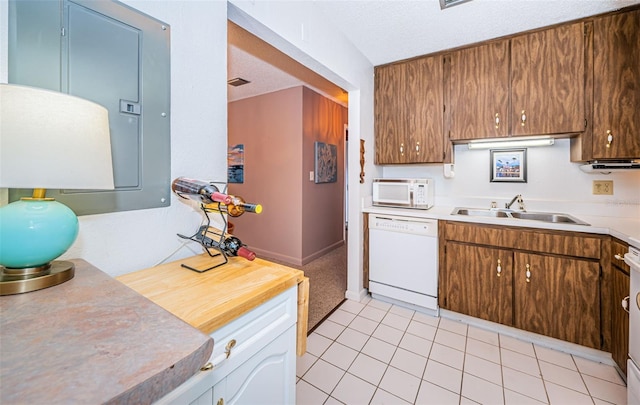 kitchen with a textured ceiling, white appliances, light tile patterned floors, and sink