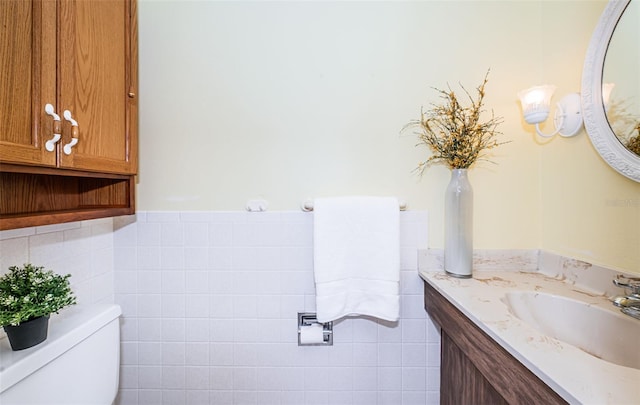 bathroom featuring vanity, toilet, and tile walls