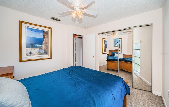 carpeted bedroom with ceiling fan, a textured ceiling, and a closet