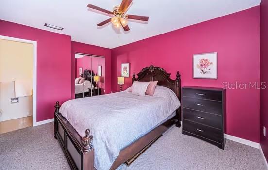 carpeted bedroom featuring ceiling fan and a closet