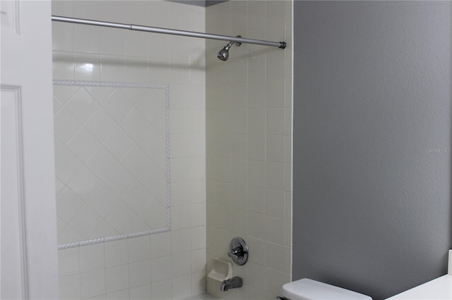 bathroom featuring toilet and tiled shower / bath