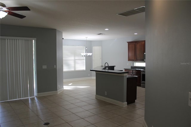 kitchen with ceiling fan with notable chandelier, sink, pendant lighting, stainless steel stove, and light tile patterned flooring