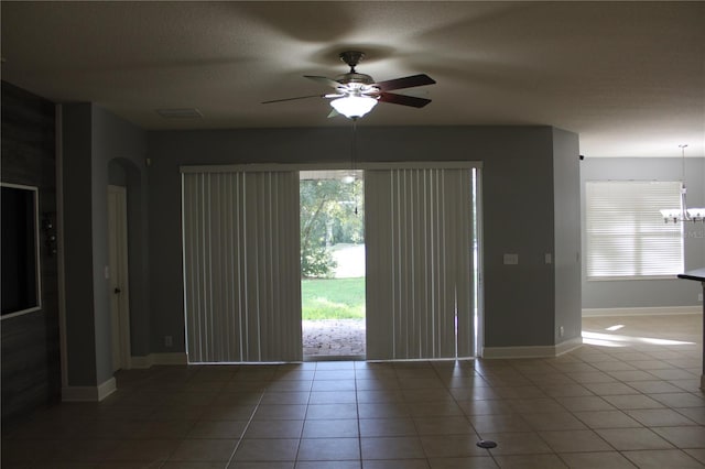 spare room featuring a textured ceiling, tile patterned flooring, and ceiling fan with notable chandelier