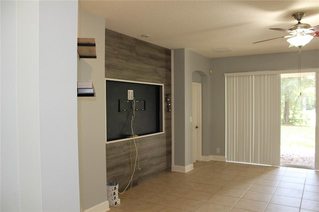 interior space with ceiling fan, light tile patterned flooring, and a textured ceiling