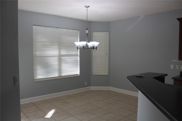 unfurnished dining area featuring light tile patterned floors and a notable chandelier