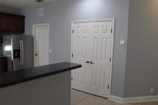 kitchen with dark brown cabinets, light tile patterned flooring, and stainless steel fridge with ice dispenser