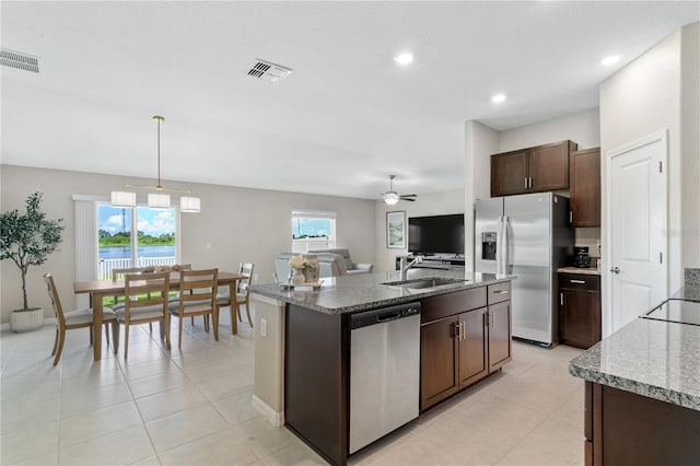 kitchen with pendant lighting, a kitchen island with sink, sink, appliances with stainless steel finishes, and dark brown cabinets