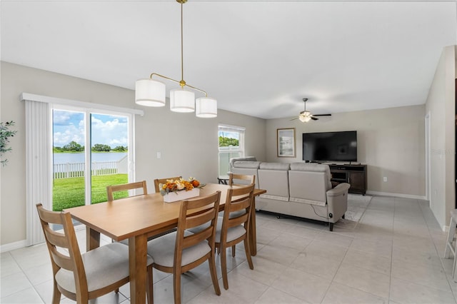 dining area with ceiling fan, a water view, and light tile patterned floors