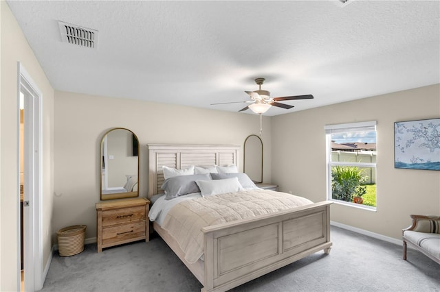 carpeted bedroom with ceiling fan and a textured ceiling