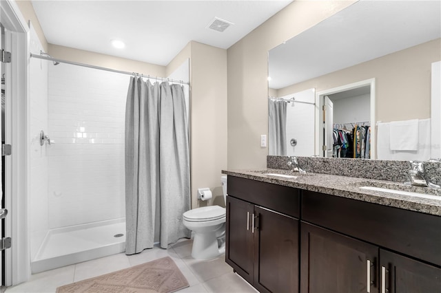 bathroom featuring tile patterned floors, walk in shower, vanity, and toilet