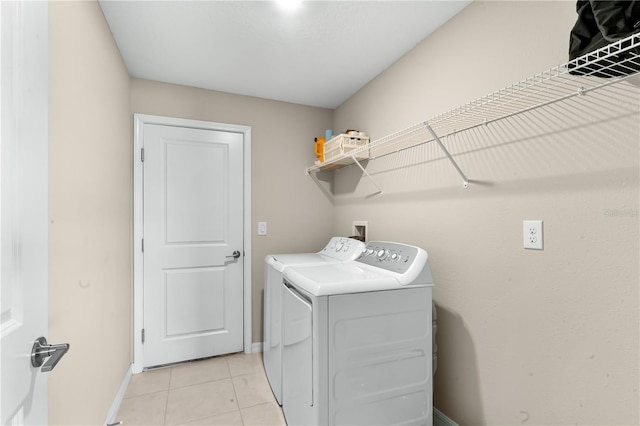 clothes washing area featuring light tile patterned floors and washing machine and dryer