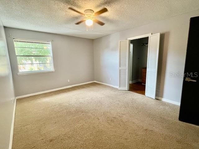 carpeted empty room featuring a textured ceiling and ceiling fan