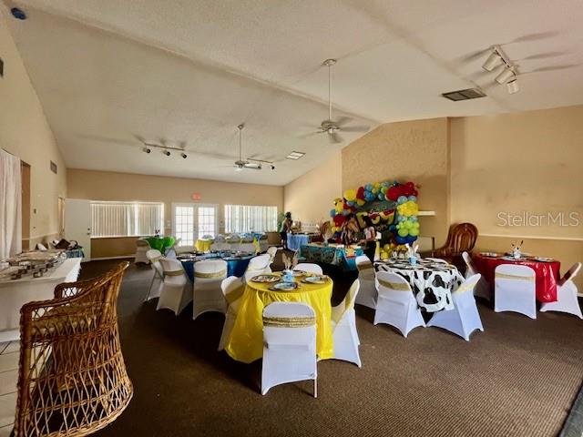 dining area featuring track lighting, vaulted ceiling, and ceiling fan