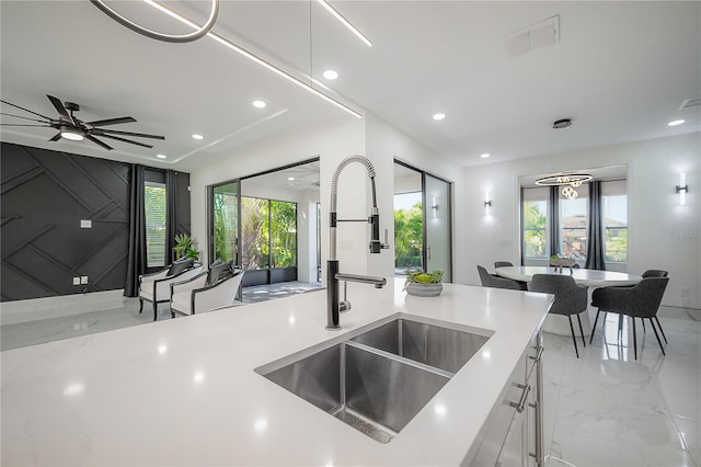 kitchen with ceiling fan with notable chandelier, white cabinetry, a healthy amount of sunlight, and sink