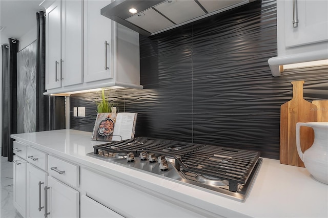 kitchen with white cabinets, ventilation hood, stainless steel gas cooktop, and tasteful backsplash