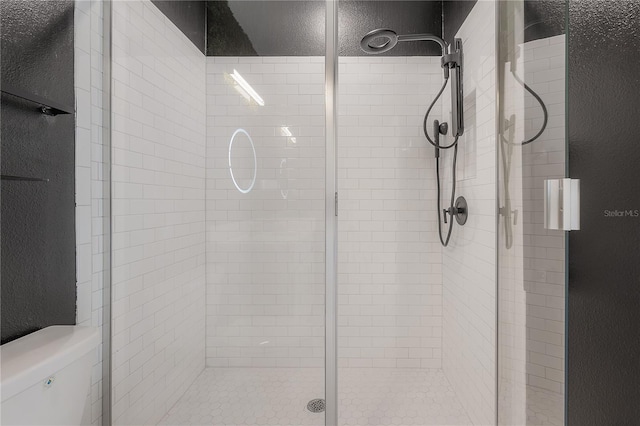 bathroom featuring a shower with shower door and toilet