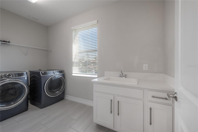 laundry room featuring cabinets, light wood-type flooring, a textured ceiling, sink, and washer and dryer