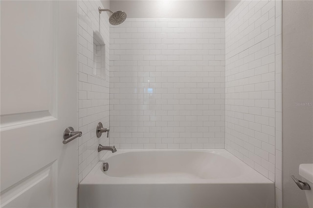 bathroom with tiled shower / bath combo and toilet