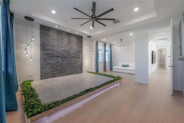 interior space featuring a tray ceiling, a chandelier, and light hardwood / wood-style floors