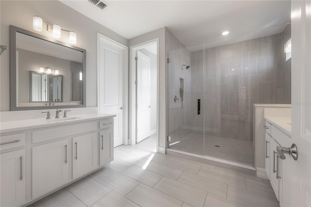 bathroom featuring a shower with door and vanity