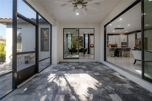 unfurnished sunroom featuring ceiling fan and a healthy amount of sunlight