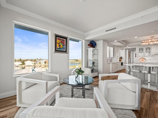 living room with hardwood / wood-style floors, sink, a water view, and crown molding