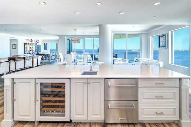 bar featuring pendant lighting, light hardwood / wood-style floors, a water view, and wine cooler