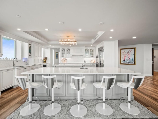 kitchen with white cabinets, a breakfast bar, light wood-type flooring, and a large island with sink