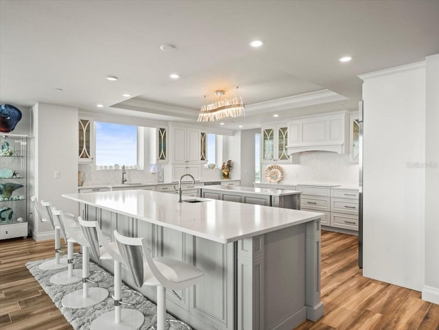 kitchen with hardwood / wood-style flooring, a large island, a raised ceiling, and backsplash