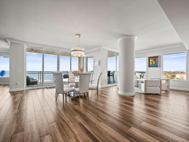 dining area with a chandelier, crown molding, a water view, and dark wood-type flooring