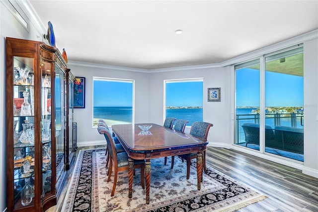 dining space featuring hardwood / wood-style floors, a water view, and ornamental molding