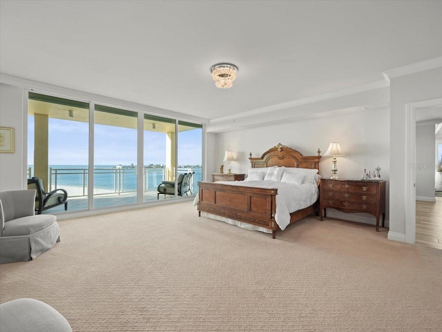 carpeted bedroom with access to exterior, a water view, floor to ceiling windows, and ornamental molding