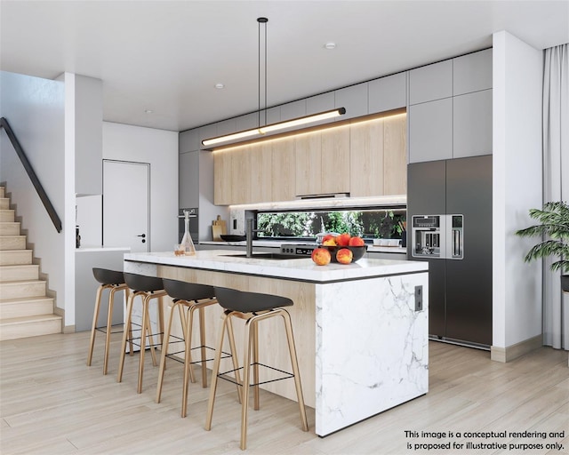 kitchen featuring black built in refrigerator, an island with sink, a breakfast bar, and pendant lighting