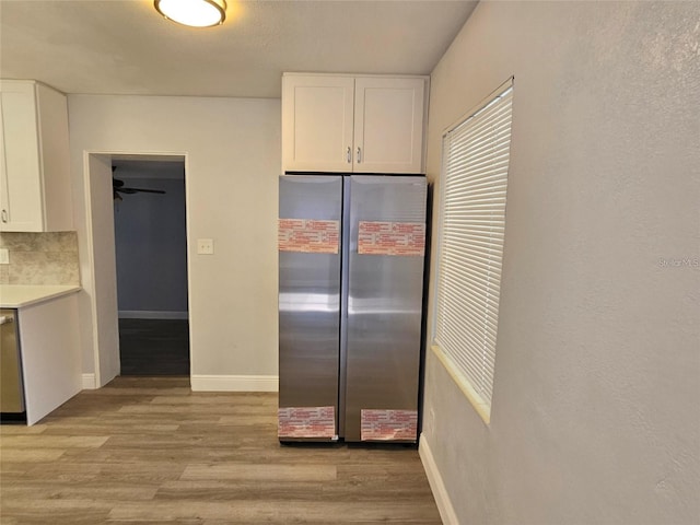 kitchen featuring decorative backsplash, ceiling fan, light wood-type flooring, white cabinetry, and stainless steel appliances