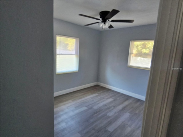 empty room with hardwood / wood-style floors, ceiling fan, and a healthy amount of sunlight