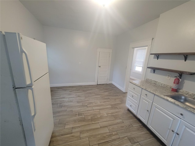 kitchen featuring light wood-type flooring, white fridge, white cabinetry, and vaulted ceiling