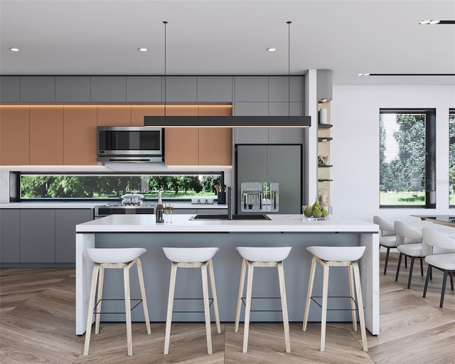 kitchen with built in refrigerator, a breakfast bar, pendant lighting, and gray cabinets