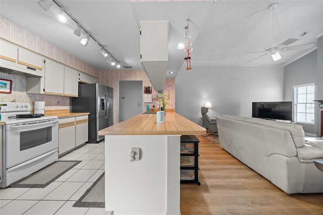 kitchen featuring a breakfast bar, electric range, open floor plan, stainless steel fridge, and wallpapered walls