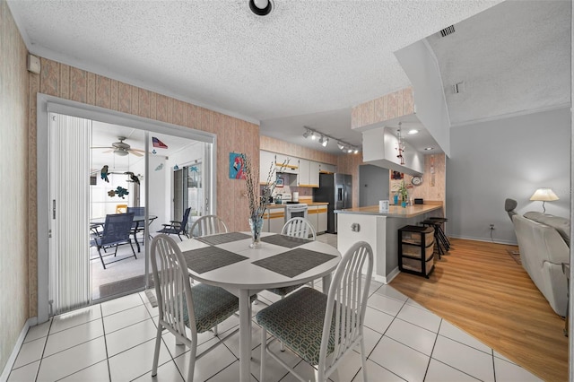 dining space featuring a textured ceiling, light tile patterned flooring, baseboards, wallpapered walls, and crown molding