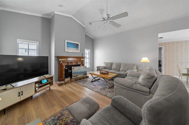 living room featuring a textured ceiling, lofted ceiling, wood finished floors, ornamental molding, and a brick fireplace