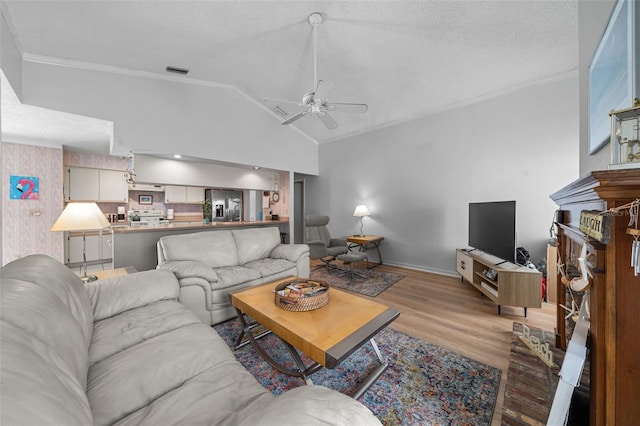 living room featuring lofted ceiling, visible vents, crown molding, and wood finished floors