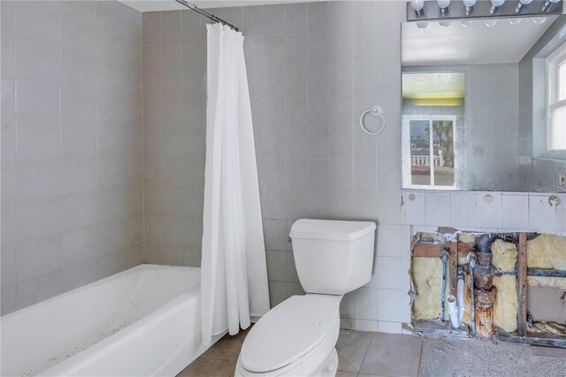 bathroom with tile patterned flooring, shower / bath combo, and tile walls