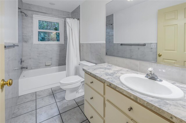 full bathroom featuring tile patterned floors, toilet, shower / bath combo with shower curtain, vanity, and tile walls