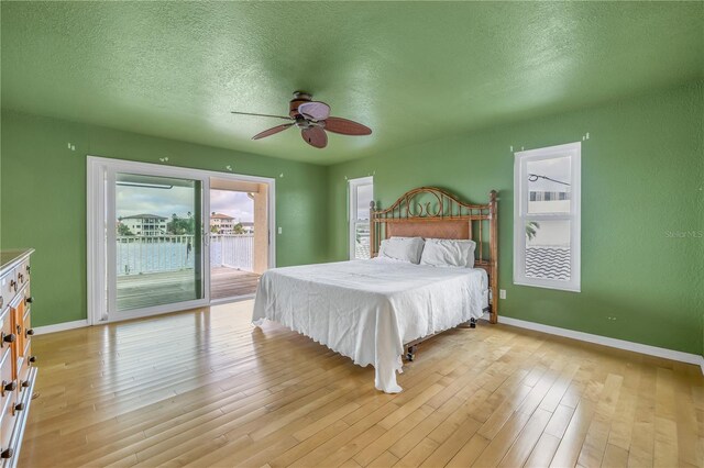 bedroom with access to exterior, a textured ceiling, light hardwood / wood-style floors, and ceiling fan