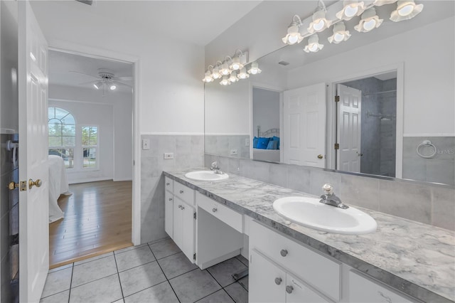 bathroom with tile patterned floors, ceiling fan, vanity, and tile walls