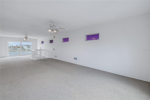 unfurnished room with carpet flooring, ceiling fan, and a water view