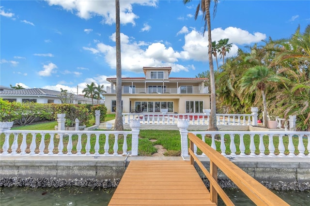 back of house with a lawn, a balcony, and a water view