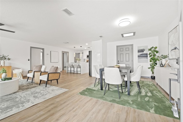 dining space with ceiling fan and light hardwood / wood-style flooring