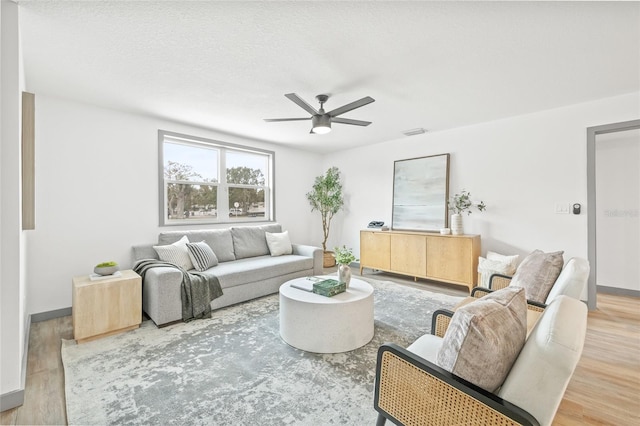 living room featuring wood-type flooring, a textured ceiling, and ceiling fan