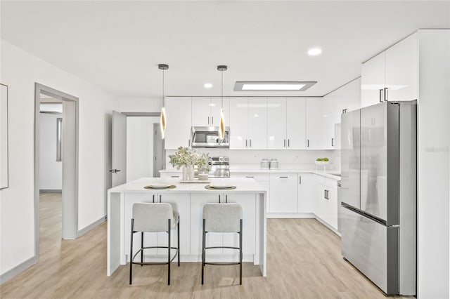 kitchen featuring white cabinetry, hanging light fixtures, stainless steel appliances, and light hardwood / wood-style flooring